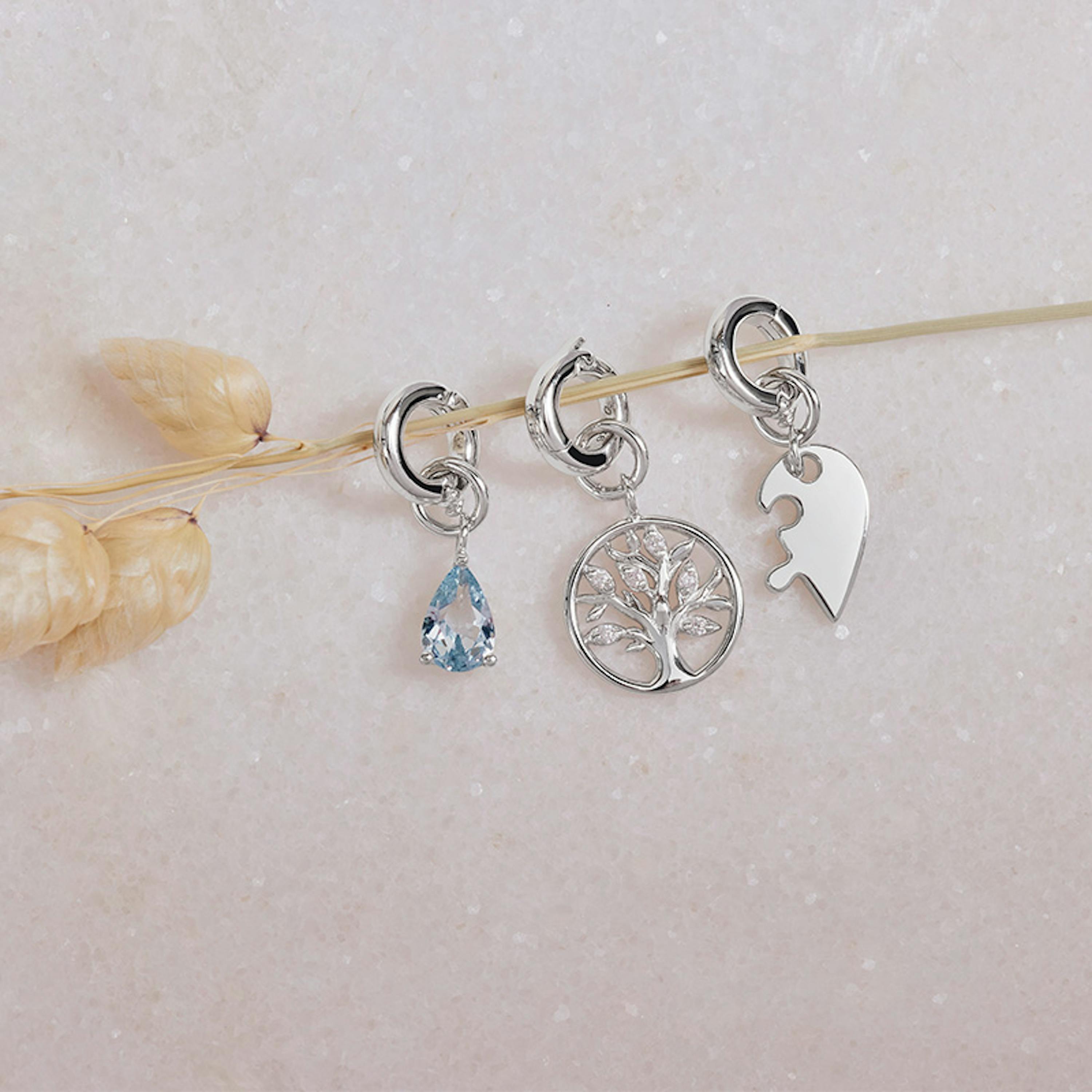 Silberne Charms mit verschiedenen Motiven wie Lebensbaum, Herz und Schmuckstein