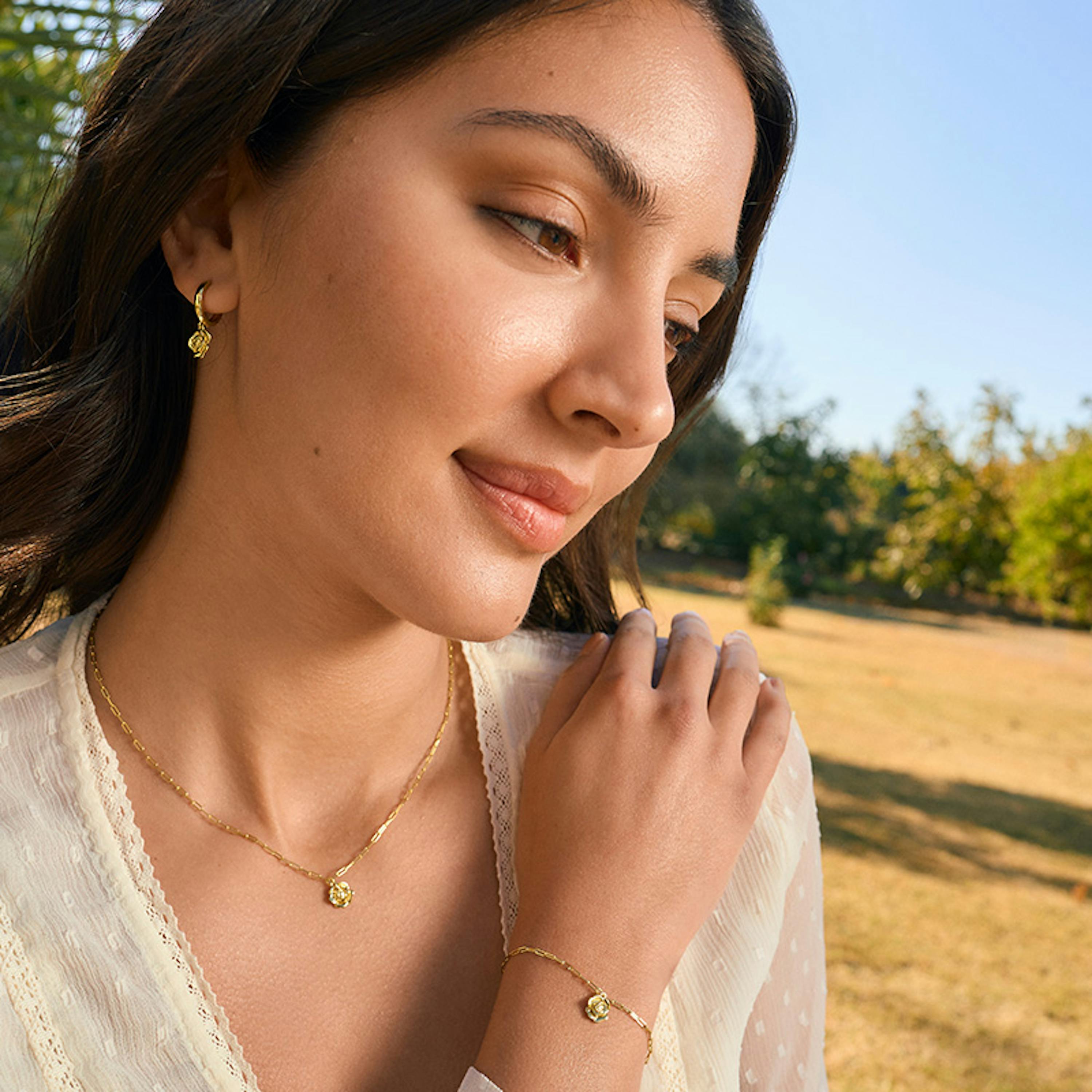 Frau trägt Goldschmuck mit Rosen Motiv
