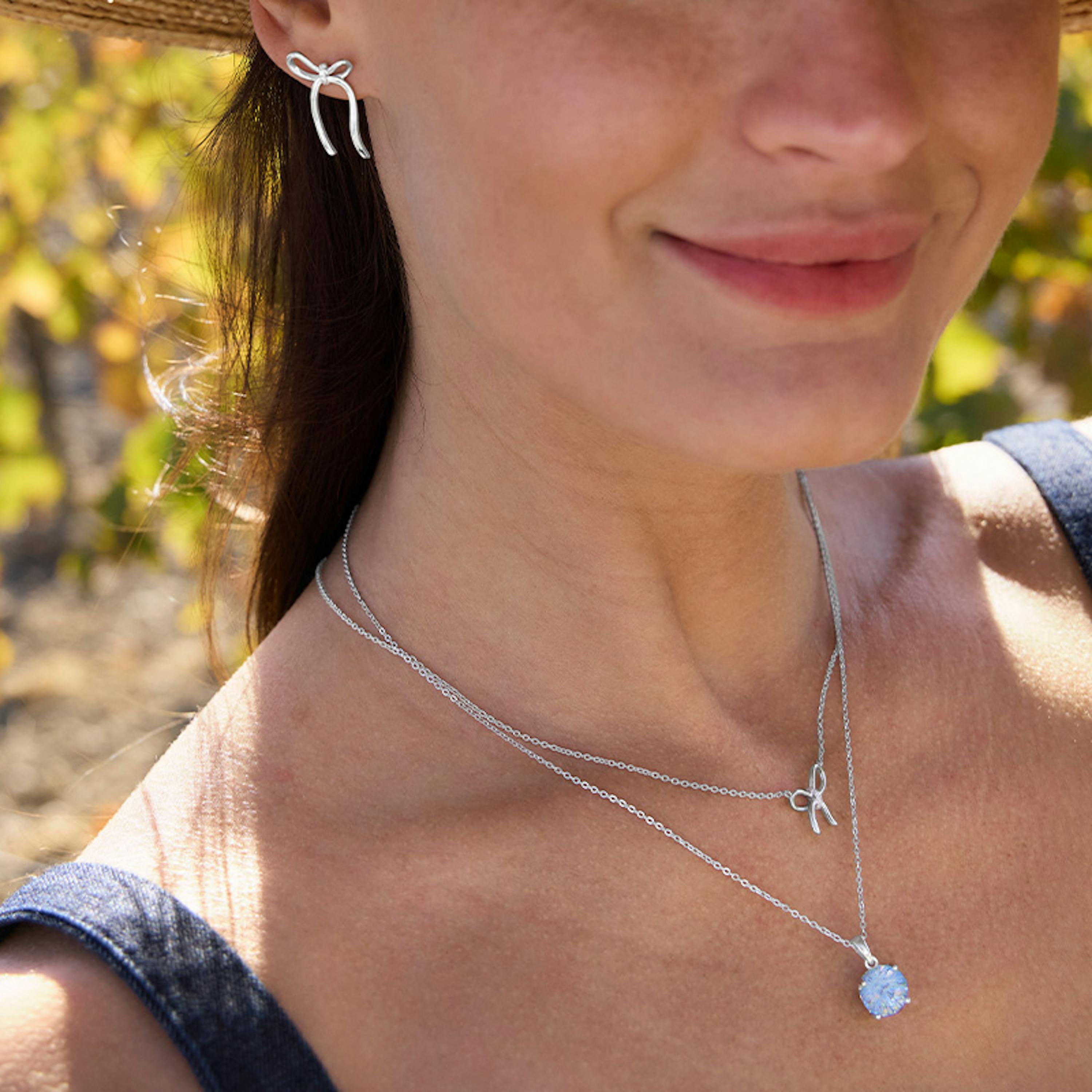 Frau trägt silbernen Schmuck mit Schleifen Optik aus der neuen Amor Spring Collection