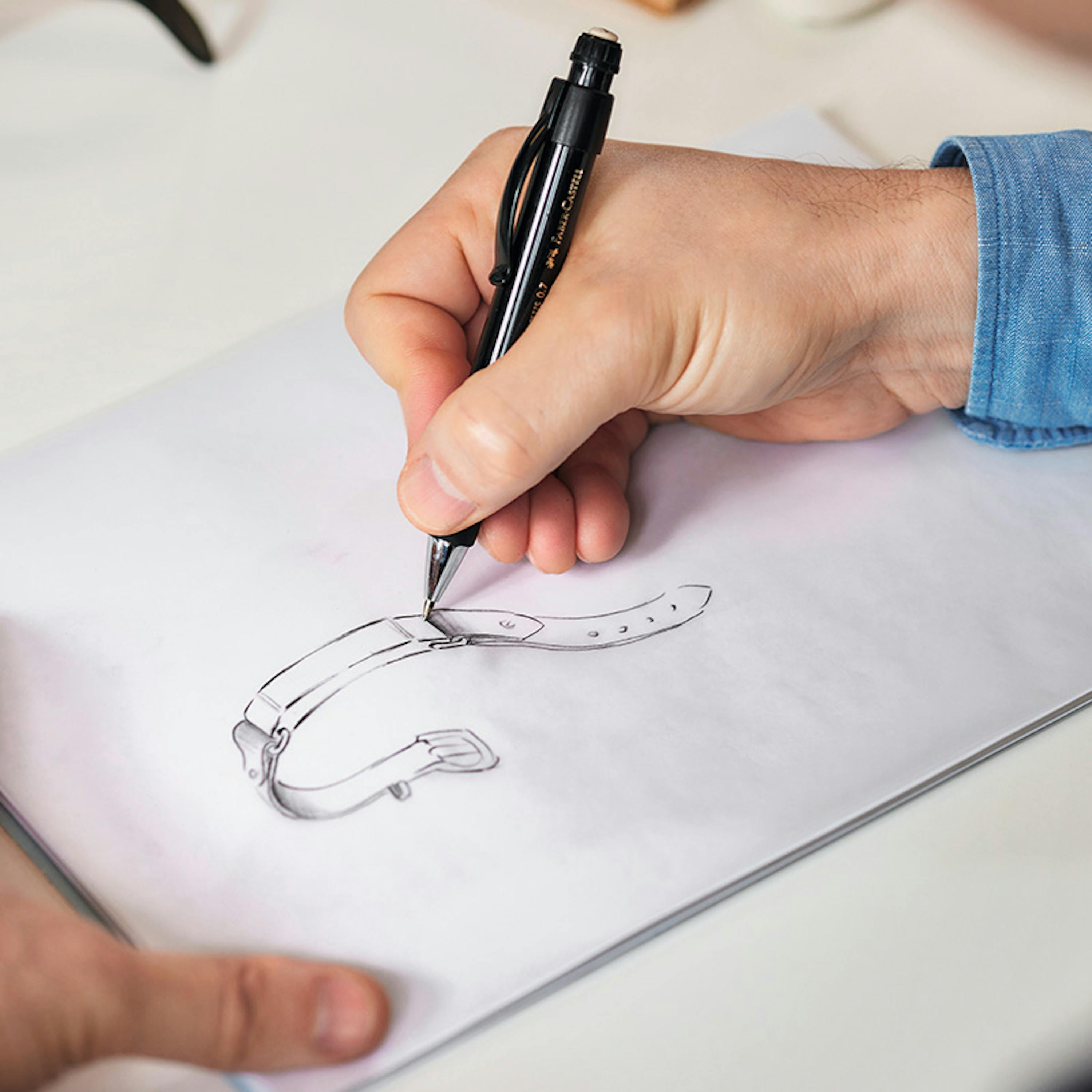 Eine Hand, die eine Zeichnung von einem Armband anlegt.