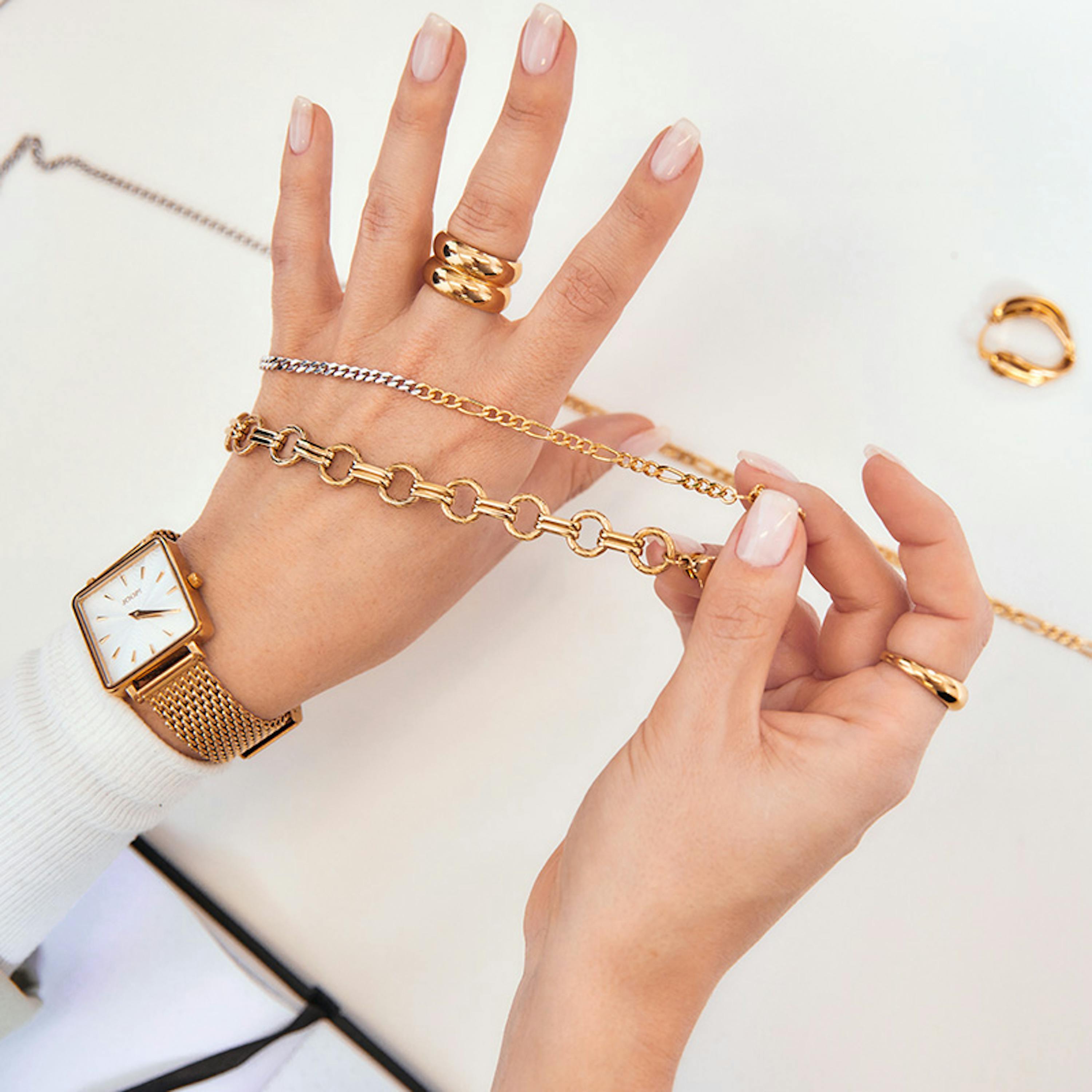 Hände, die Gold- und Silberschmuck auf Echtheit prüfen