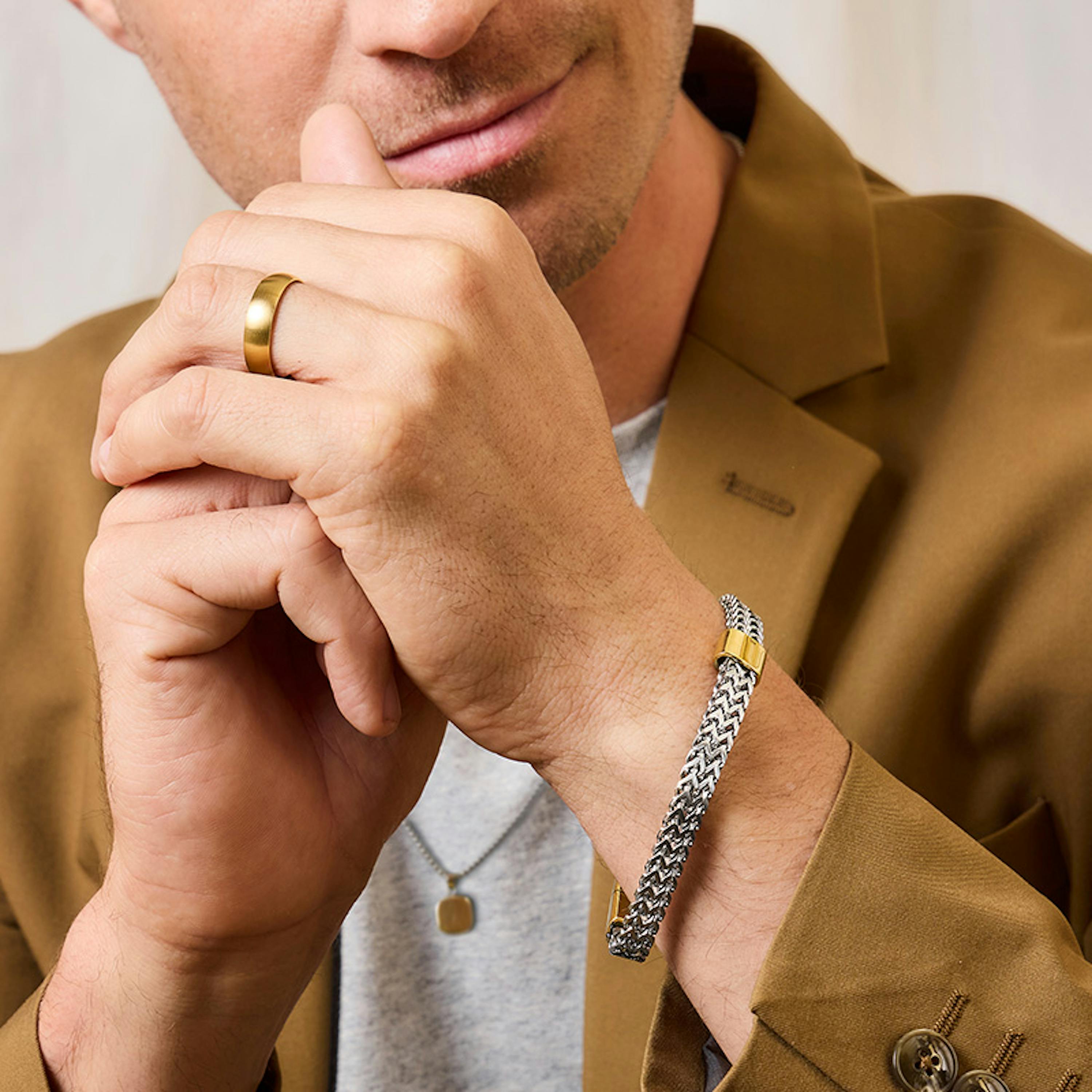Mann trägt silbernes Edelstahl Armband mit goldenen Akzenten und goldenen Ring